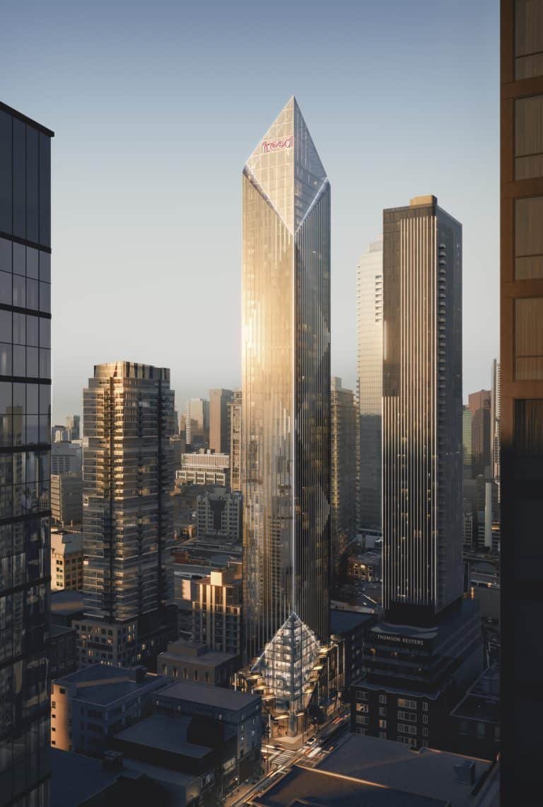 A cityscape at sunrise featuring a skyline of modern skyscrapers. The central building, known as Freed Hotel, is a tall, sleek, glass-encased structure with a pointed top, reflecting golden sunlight. Other buildings of varying heights surround it, including the elegant Freed Residences, with the sky displaying a soft, warm light.