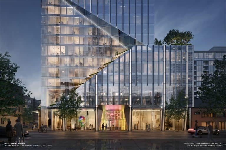 A modern high-rise building with glass facades illuminated at night. The lower portion features a distinct angular design with steps leading up to a rooftop. There are trees and a colorful display at the entrance, with a sign reading "Freed Hotel and Residences.