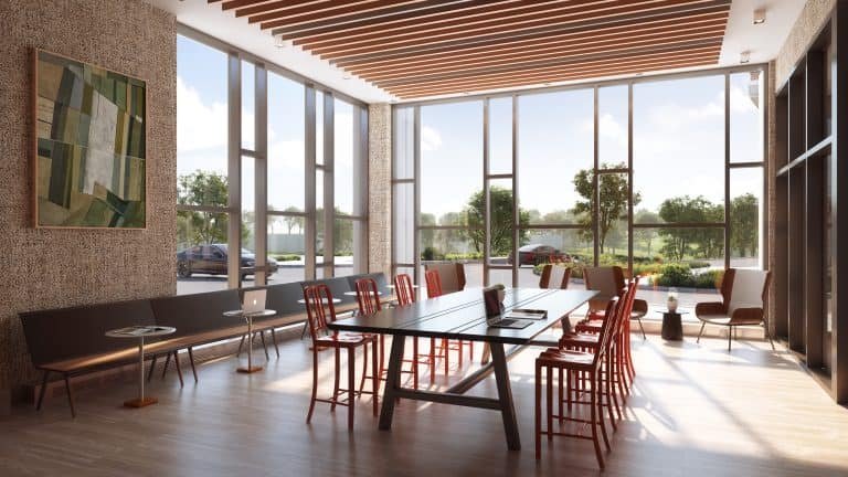 A modern conference room in a new GTA home features a large rectangular table surrounded by red chairs. Sunlight streams through expansive windows, illuminating the space. A bench with a laptop sits on the left, while framed art adorns the textured wall and greenery flourishes outside.