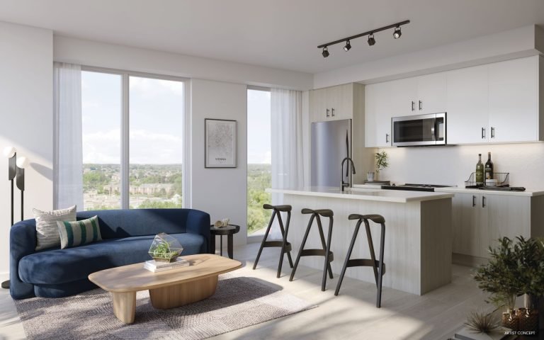 A modern living room and kitchen area in new homes features large windows, a navy sofa, a wooden coffee table, and three bar stools at a kitchen island. The kitchen boasts white cabinets, stainless steel appliances, and track lighting overhead—ideal for contemporary living in the GTA.