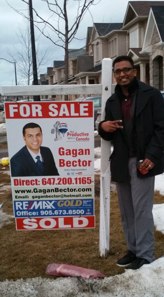 A man standing in front of a for sale sign.