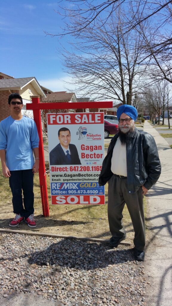 Two men standing in front of a for sale sign.