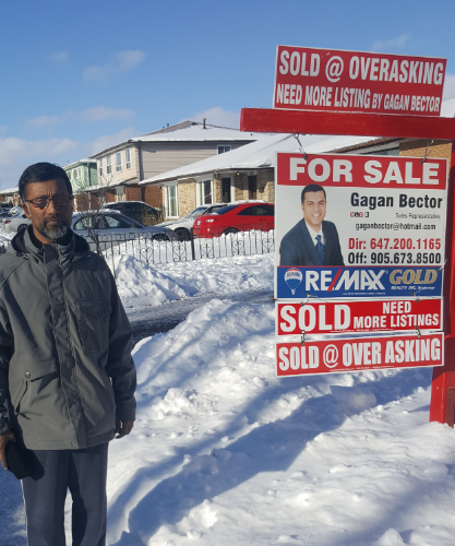 A man standing in front of a for sale sign.