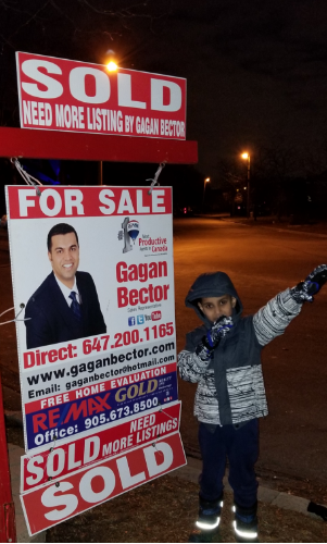 A boy standing in front of a for sale sign.